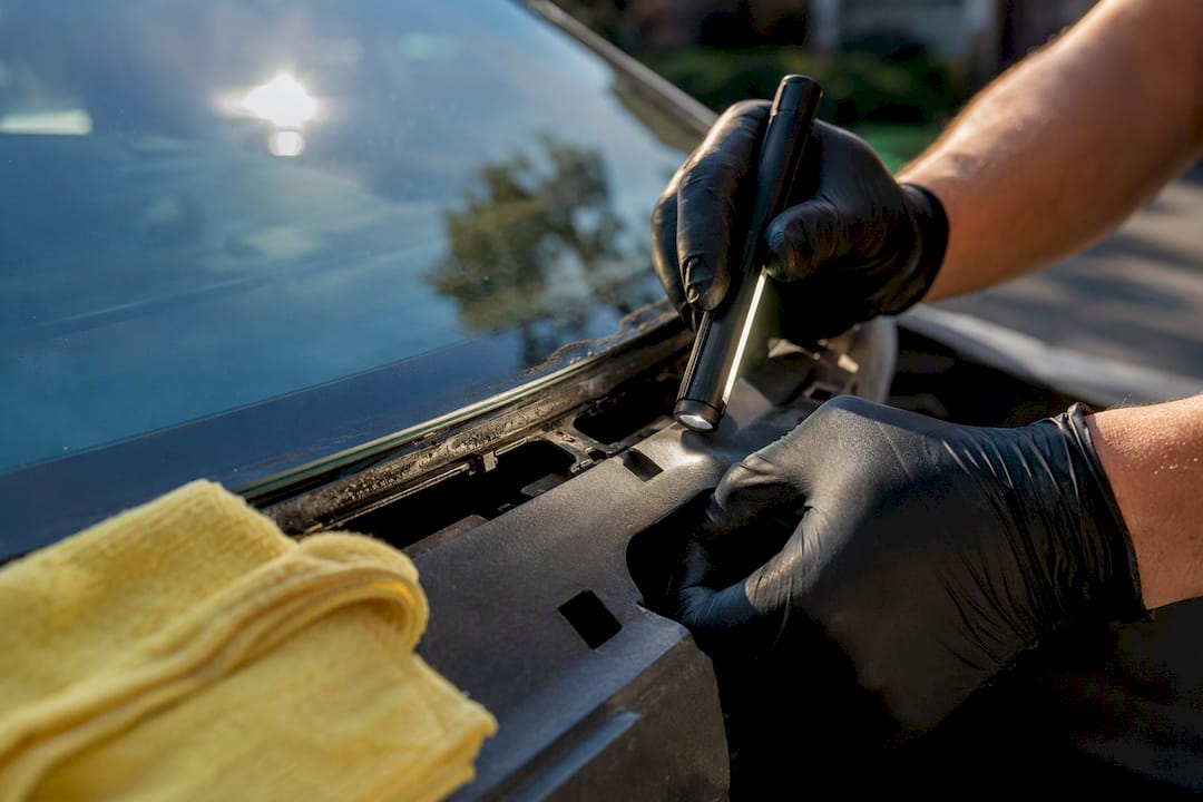 Technician inspecting windshield edge and frame