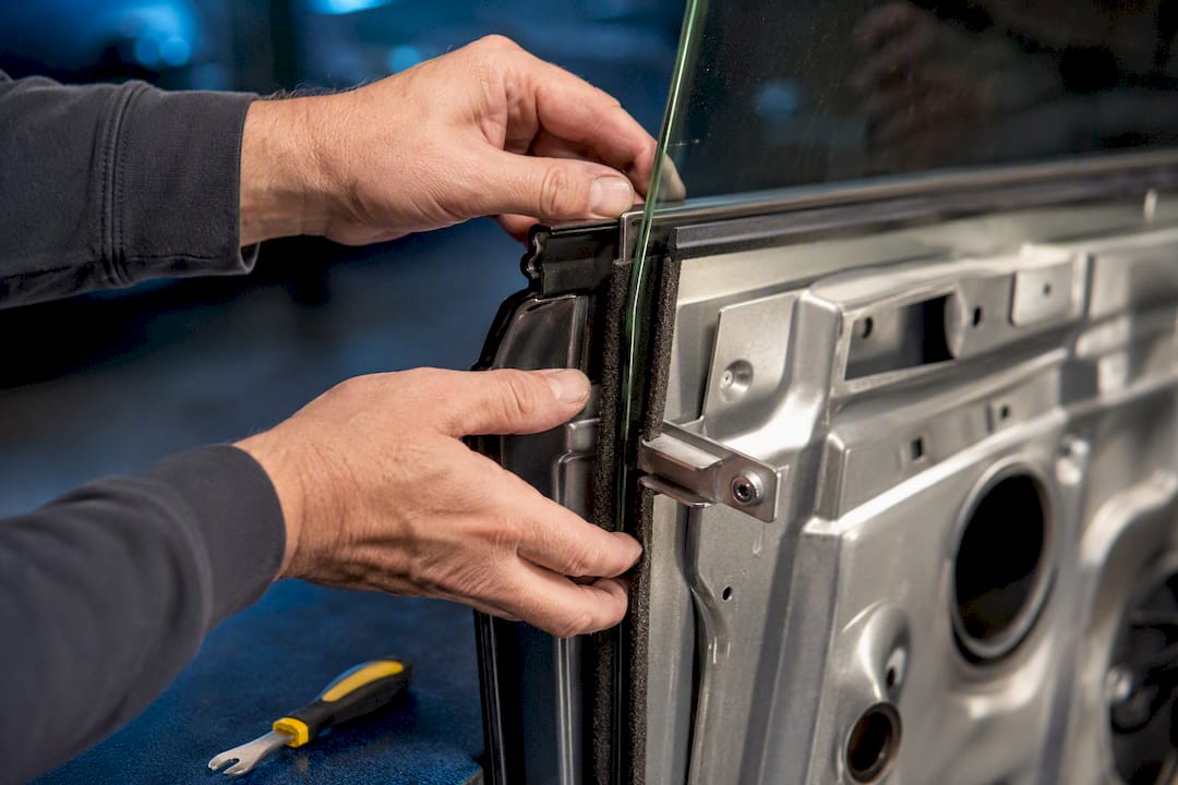 Hands reseating window glass into felt channel
