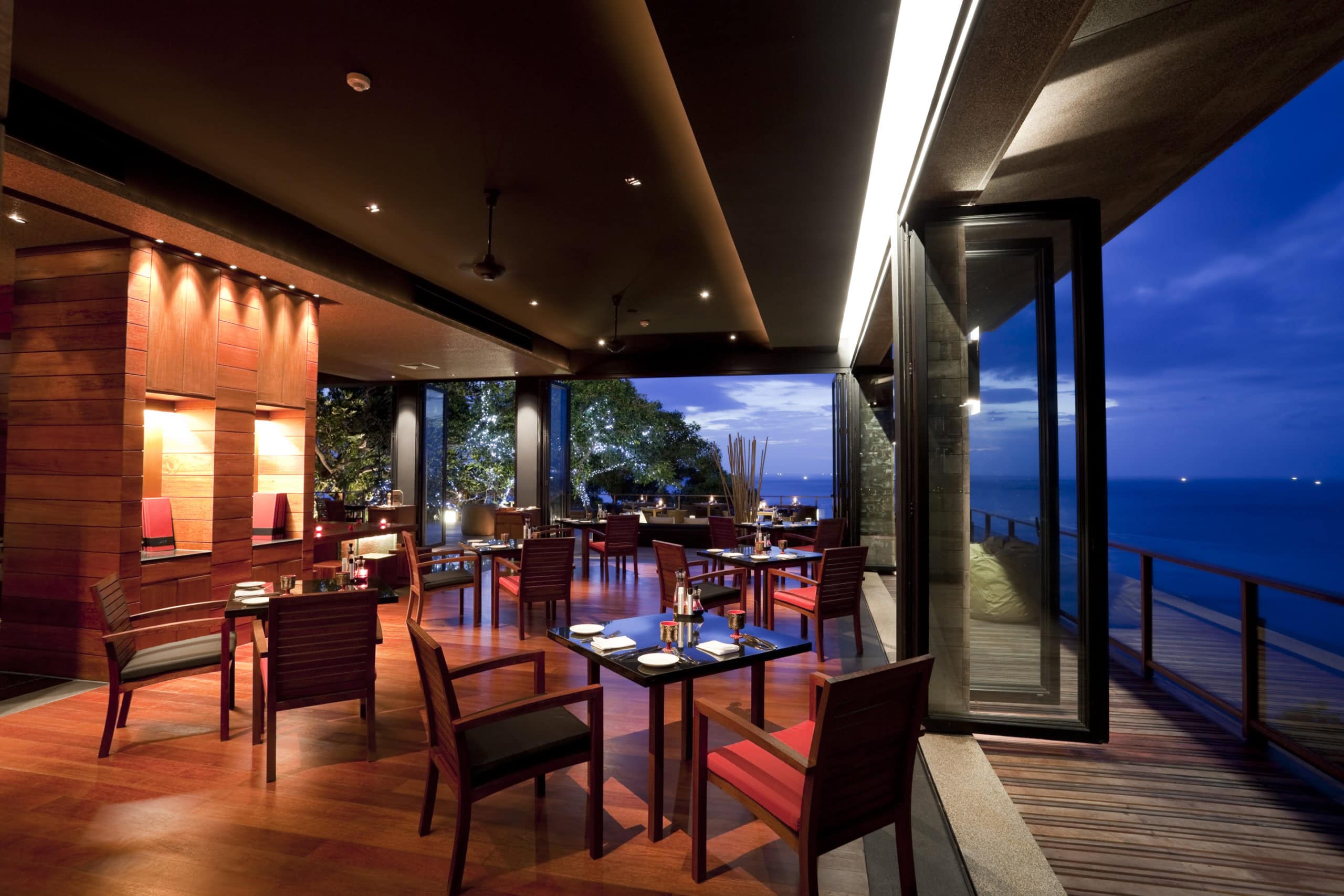 Open-air restaurant with ocean views, ambient lighting, and integrated dining atmosphere at dusk