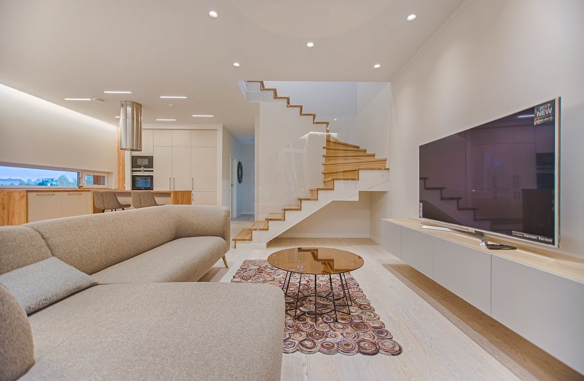 A modern living room with large smart television, neutral colors and wood accents