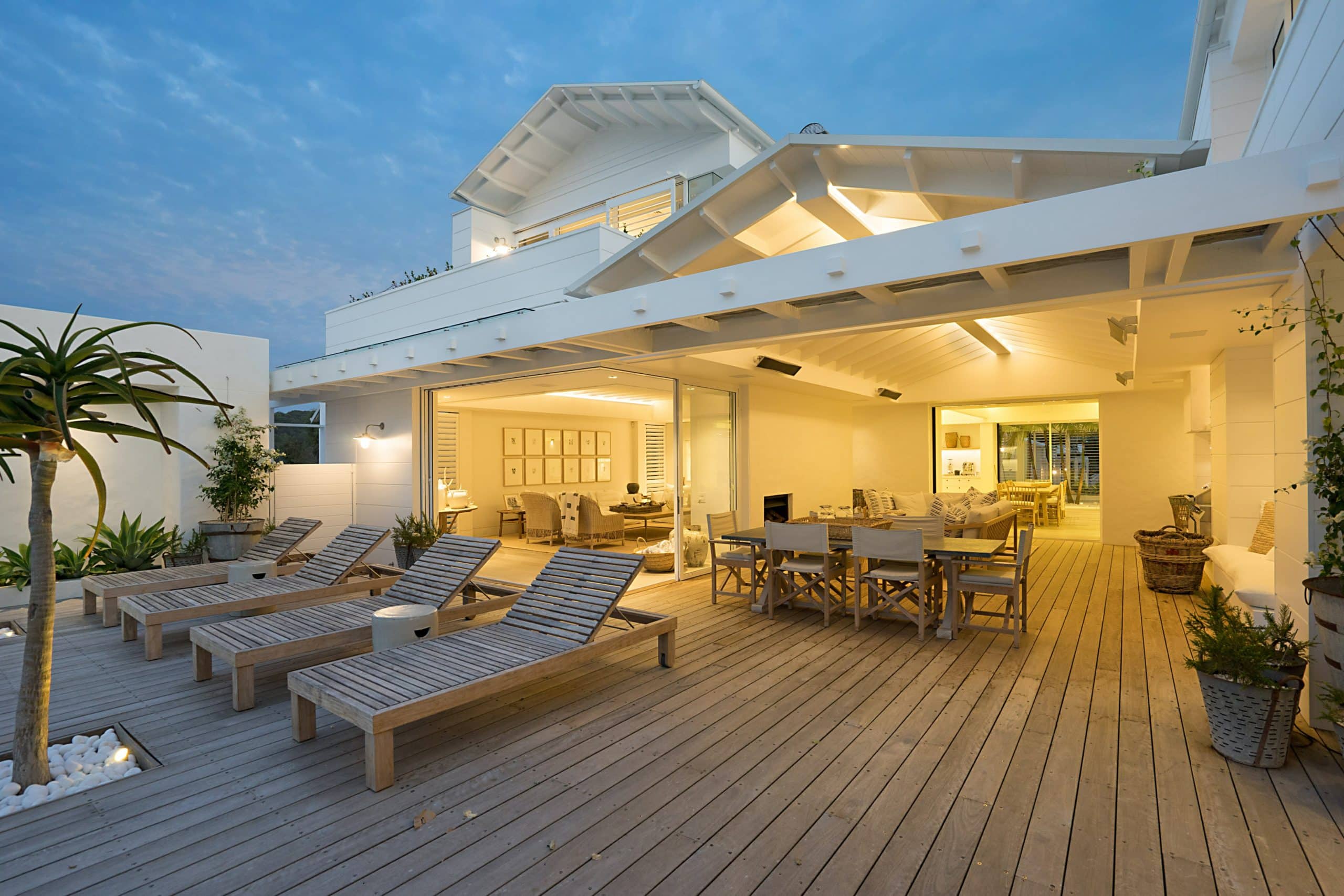 Modern home with an open-concept outdoor entertainment area with patio furniture, plants, overhead lighting and more