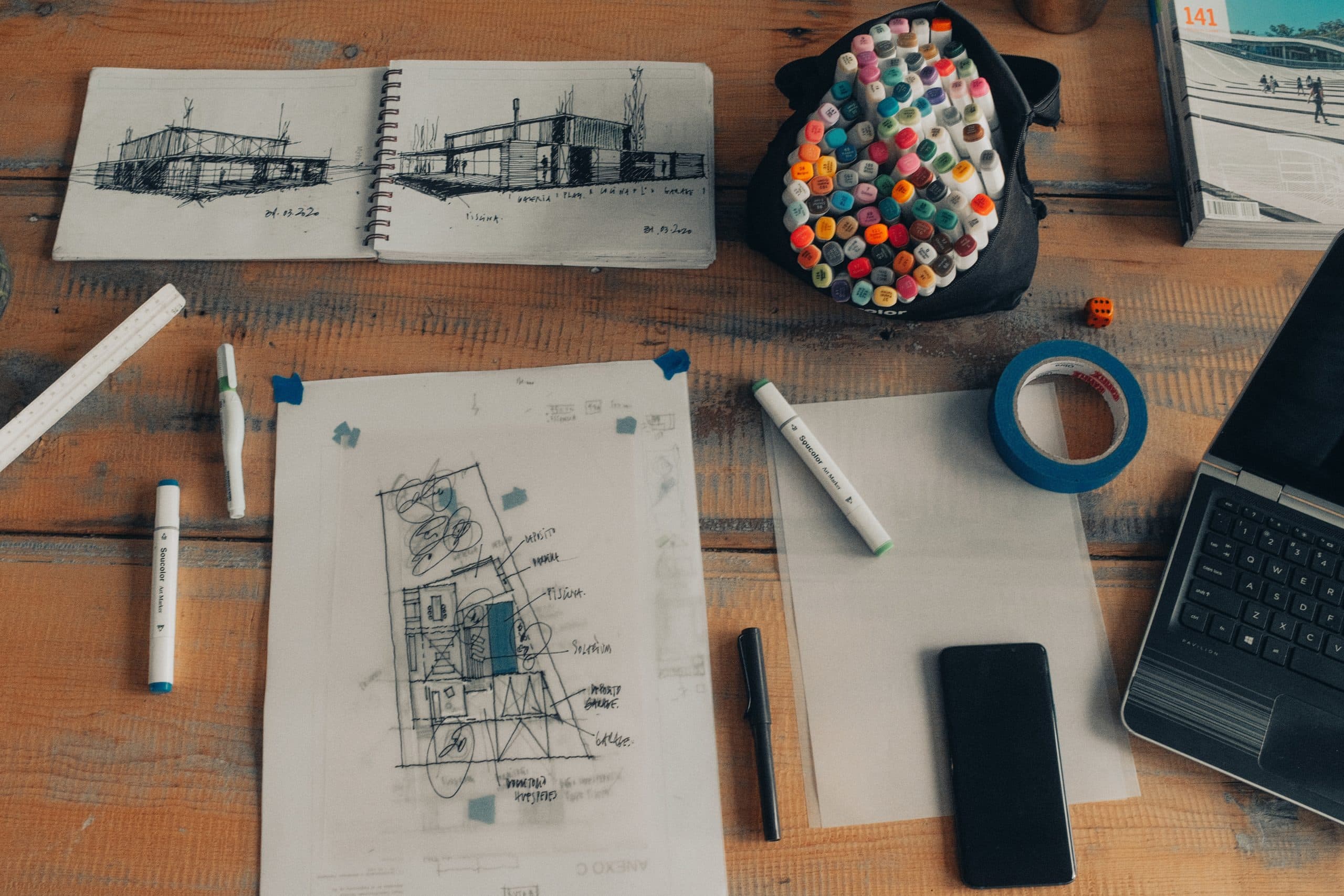 Overview of a desk with papers and drawings related to architect and contractor work duties.
