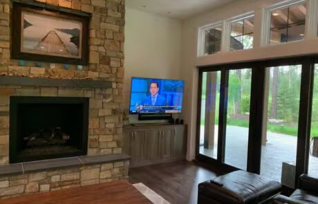 Living room AV installation with wall-mounted TV, fireplace, and patio view at Suncadia home