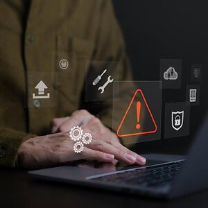 Warnsymbol für Cybersecurity-Alarm auf Laptop mit Sicherheits-Icons.