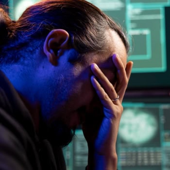 Besorgter Hacker vor Computerbildschirm mit Cybercrime-Daten.