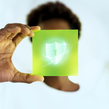 Person hält ein grünes Symbol für Cybersicherheit vor Gesicht.