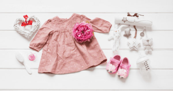 Soft pink baby dress with plush flower accessory, adorable baby toys, and accessories for infants and toddlers.