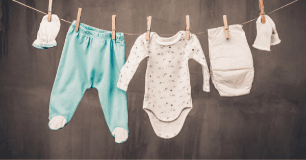 Soft baby clothes and toys hanging on a clothesline, featuring colorful onesies and baby accessories for infants.