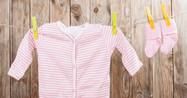 Soft pink baby clothes with socks, perfect for newborns and infants, displayed on a wooden background.