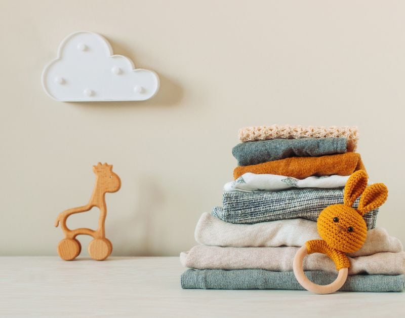 Soft baby clothes and plush toys on a neutral background, ideal for baby clothing and toy shopping.