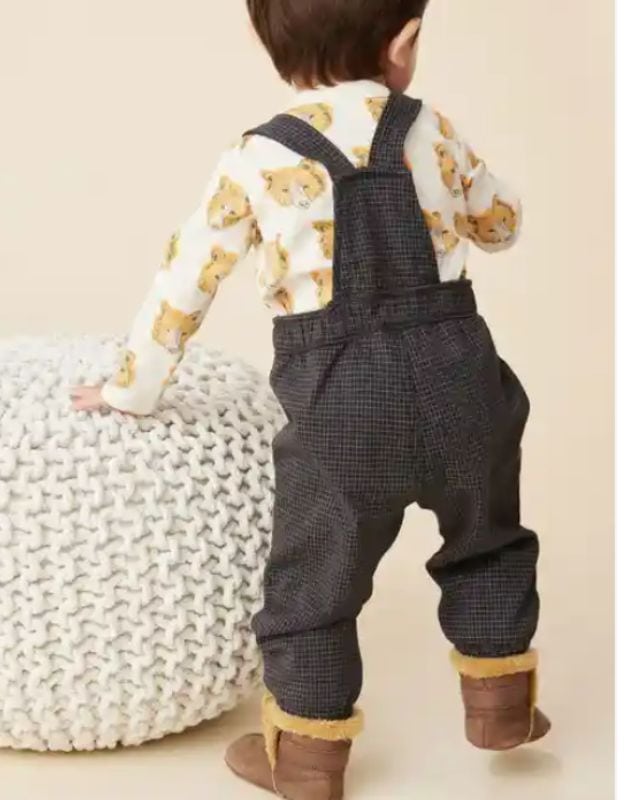 Cute toddler wearing cozy denim overalls with suspenders, adorable socks, and a lion shirt. Perfect for baby clothes and toys collection.