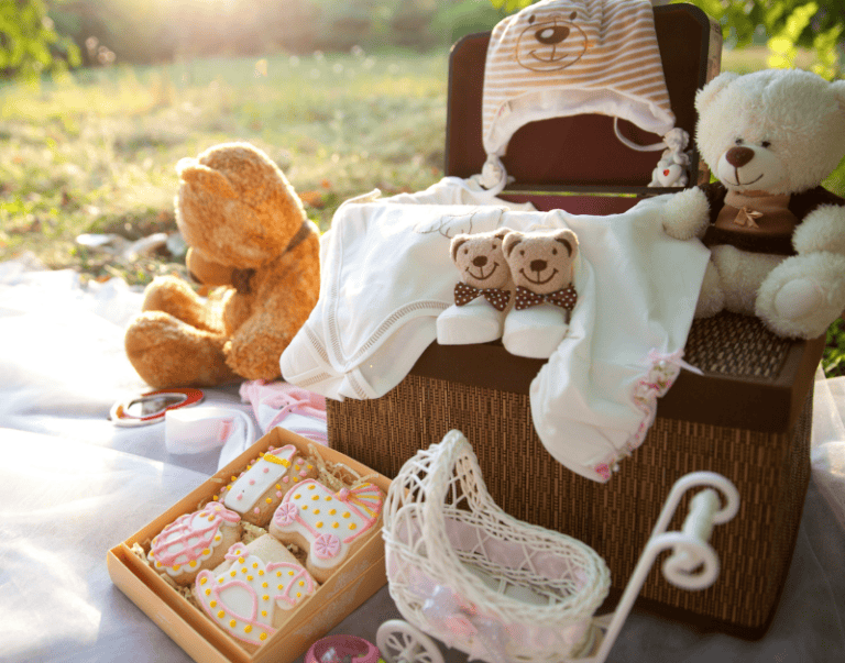 Cute baby clothes and plush toys with decorative cookies for baby shower or nursery decor.
