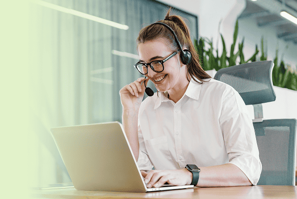 Genial customer support agent with headset communicates cheerfully call while working