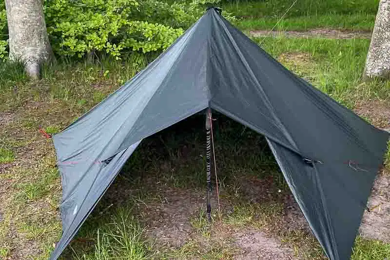 Et telt opsat i naturen med træer i baggrunden, der viser en typisk campingoplevelse.