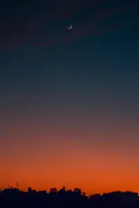 Crescent moon and fiery orange sunset horizon