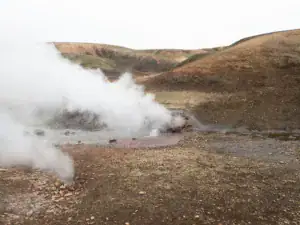 Geotermisk varm kilde med damp i et vulkansk landskab på Island – naturlig varme og rå natur