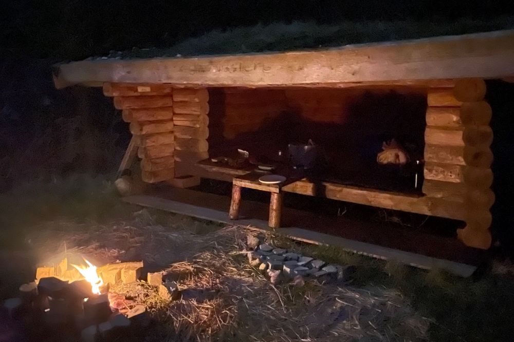 Rustik shelter bygget af træ i naturen om natten.