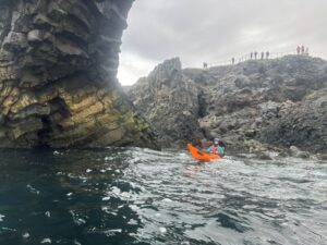 Orange kajak ligger ved klipper