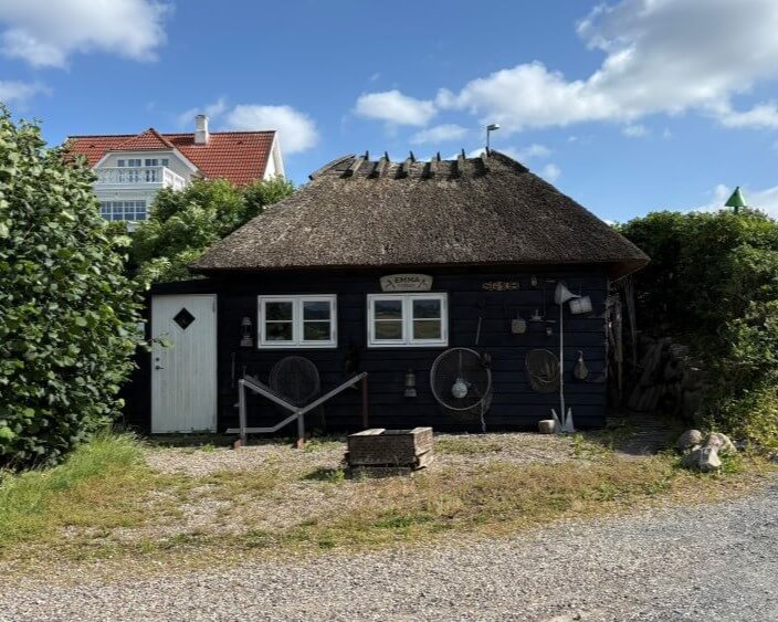 Fynsk hytte med stråtag og havn i baggrunden, perfekt til vandreture på Sydfynske Øhav.