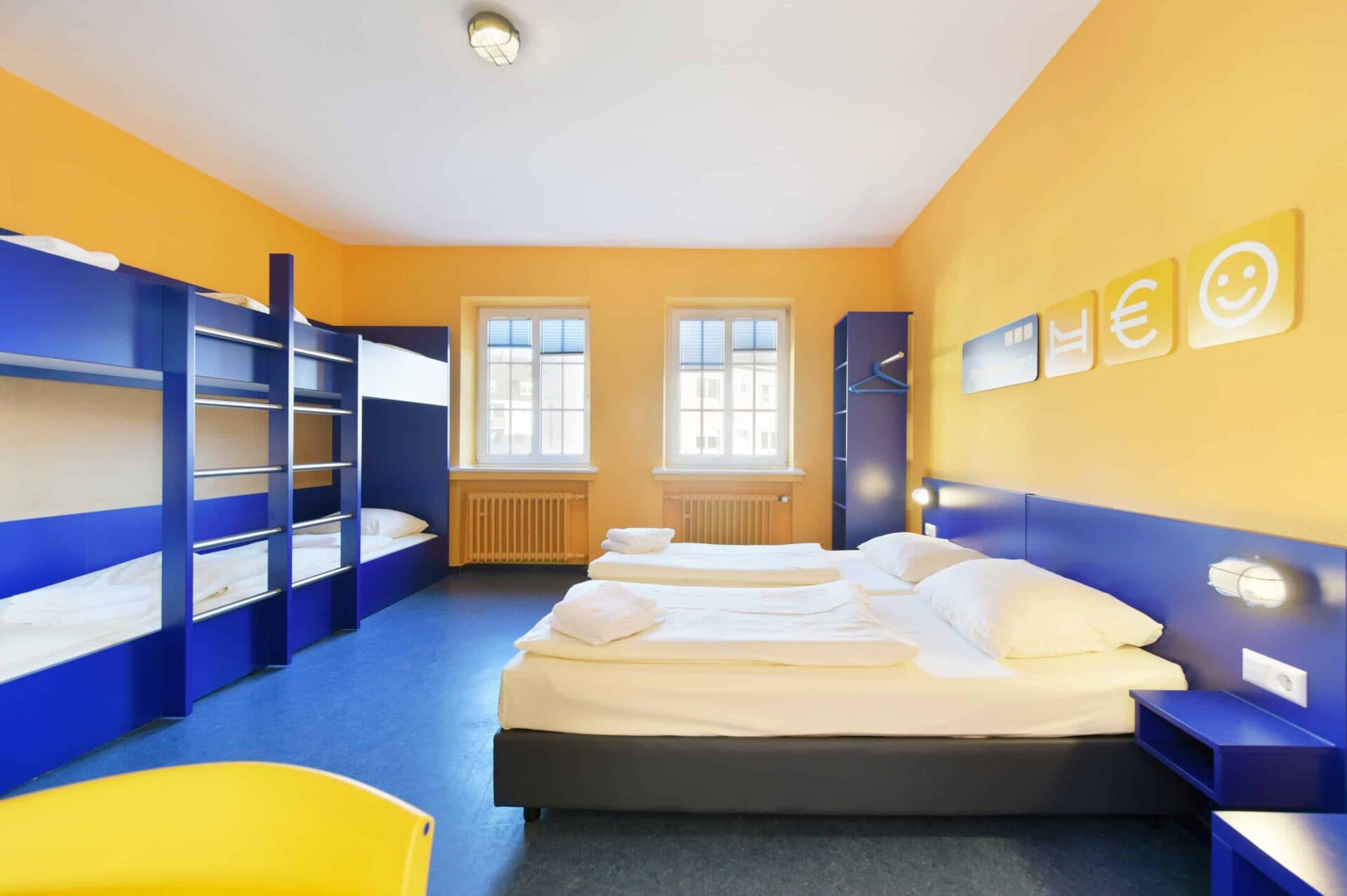 Comfort-Zimmer mit zwei Einzelbetten und zwei Etagenbetten für 6 Personen, Schrank und zwei Fenster.