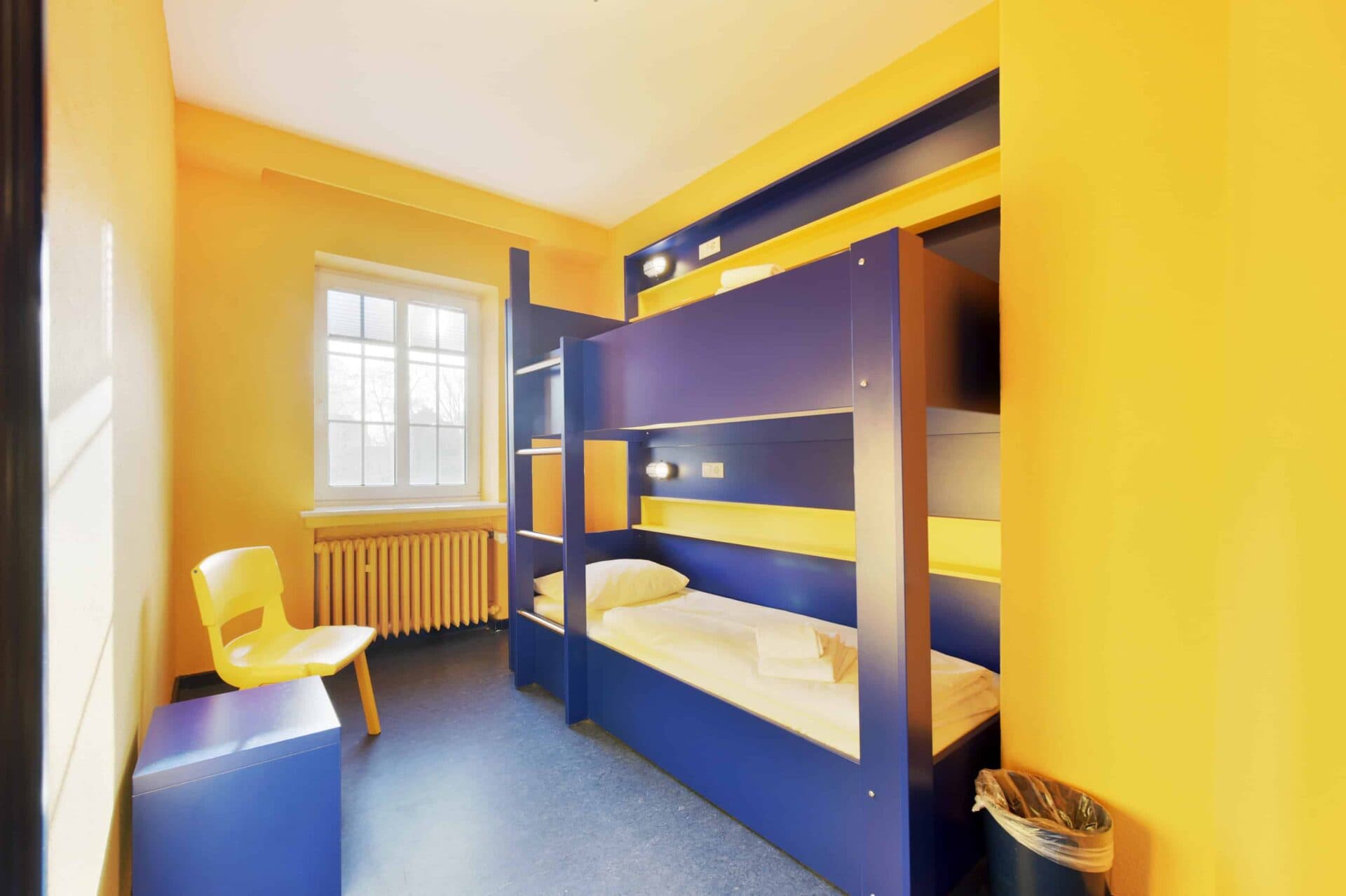 Comfort-Zimmer mit einem Etagenbett für zwei Personen, Stuhl und Fenster.