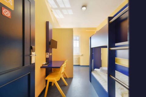 Economy-Zimmer mit einem Etagenbett für 2 Personen, einem Schreibtisch, zwei Stühlen, TV und Fenster.