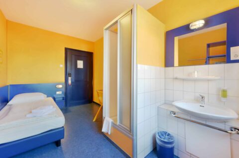 Economy-Zimmer mit einem Einzelbett, einem Waschbecken und eigener Dusche.