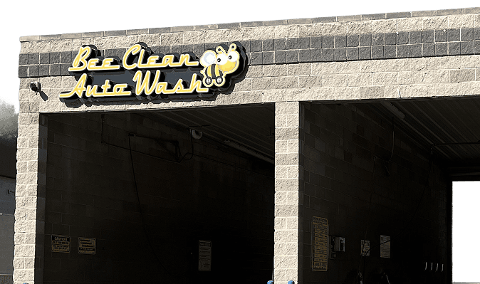 Bee Clean Auto Wash building exterior with bright signage featuring a cartoon bee logo for a professional car wash service.