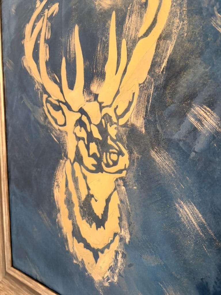 Abstract painting of a deer with large antlers in yellow and blue tones.