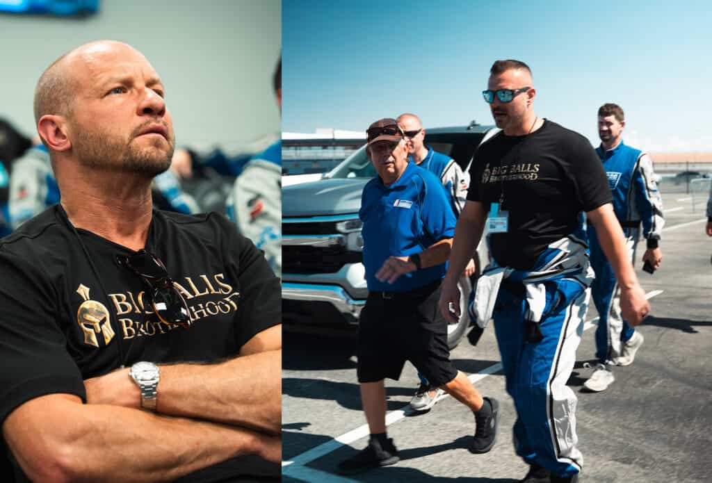 Michael driving race car with Big Balls Brotherhood team members in pit lane, showcasing racing team spirit and camaraderie.
