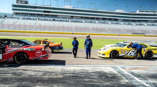 Fast race cars at the NASCAR track with team members preparing for a race event at Big Balls Brotherhood.
