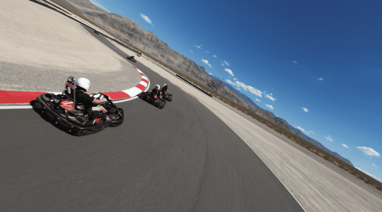 High-speed go-kart racing on a track with scenic desert mountains, thrilling competitive racing experience, outdoor go-kart track adventure, Big Balls Brotherhood themed motorsport event, adrenaline-fueled racing fun.
