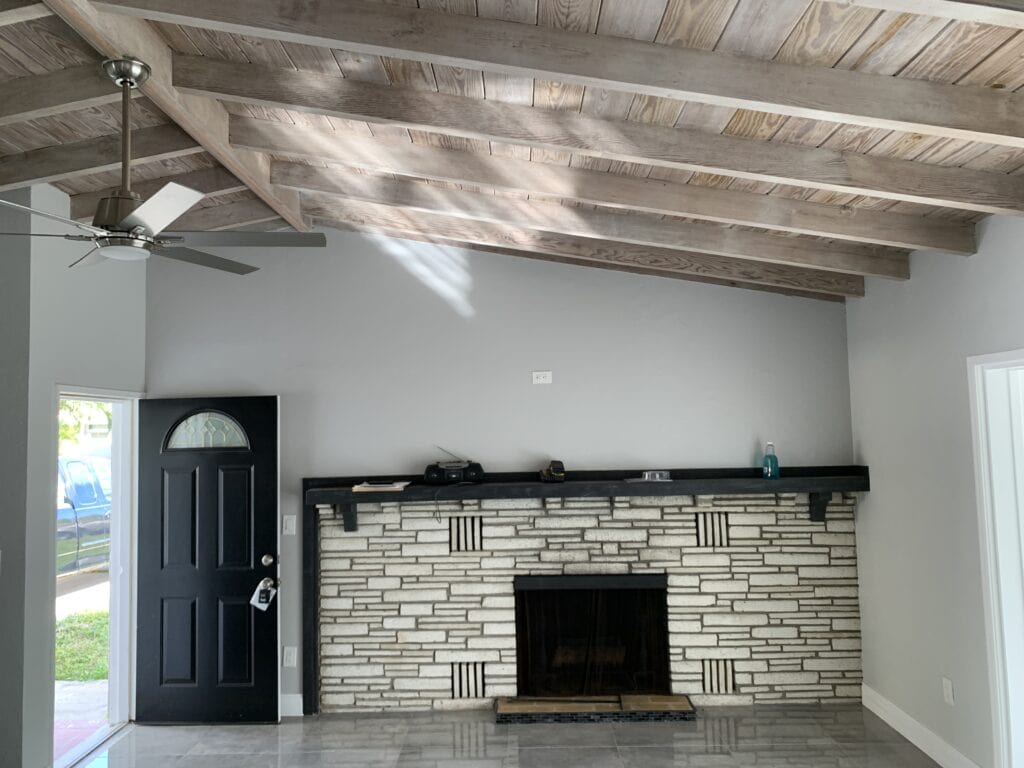 Living room with fireplace and ceiling beams during make-ready repairs