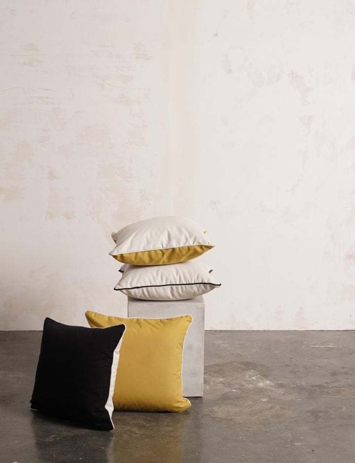 Cojines Fara en negro, amarillo y blanco apilados sobre un pedestal