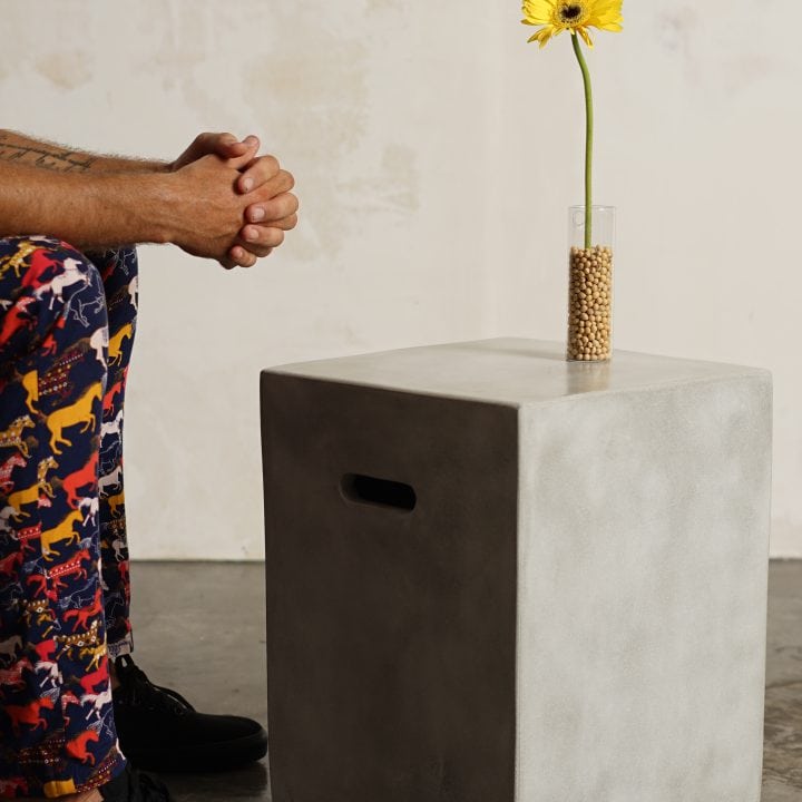 Mesa Concrete Square de hormigón con un jarrón y una flor, detalle
