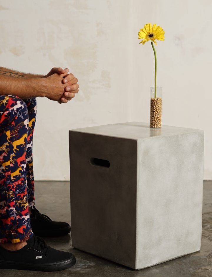 Mesa Concrete Square de hormigón con un jarrón y una flor, detalle