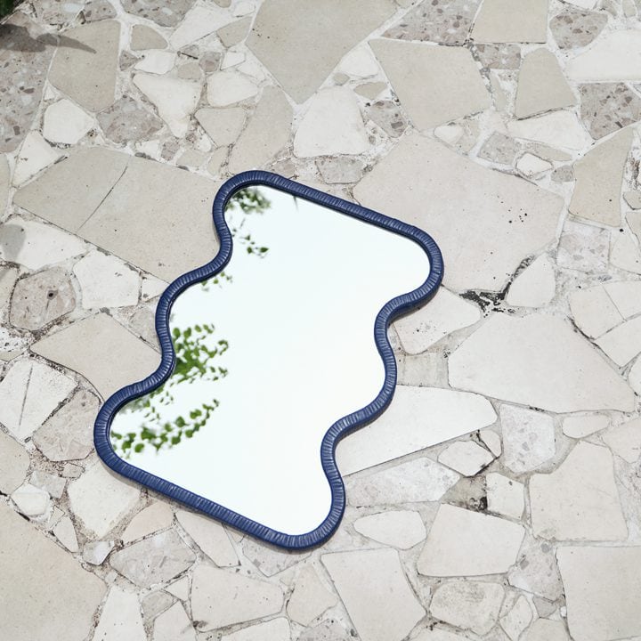 Espejo de ratán azul Lima sobre un suelo de piedra