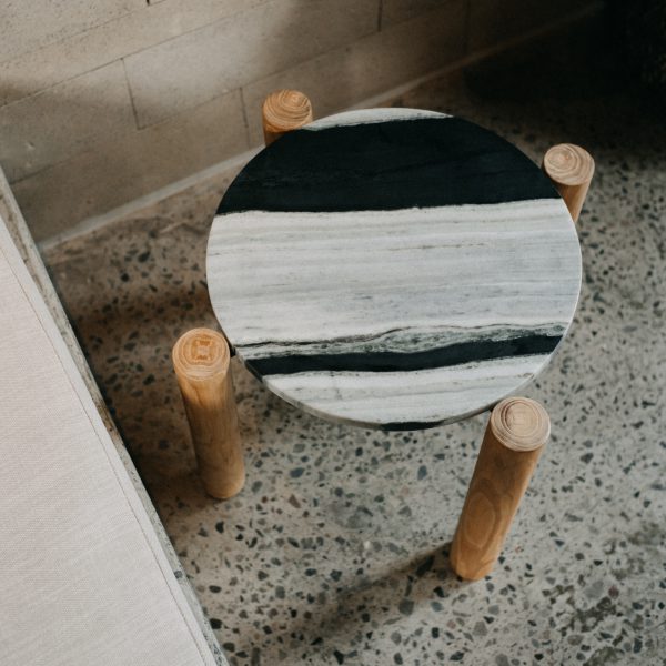 Mesa auxiliar de mármol y teca Panda Mini junto a un sofá
