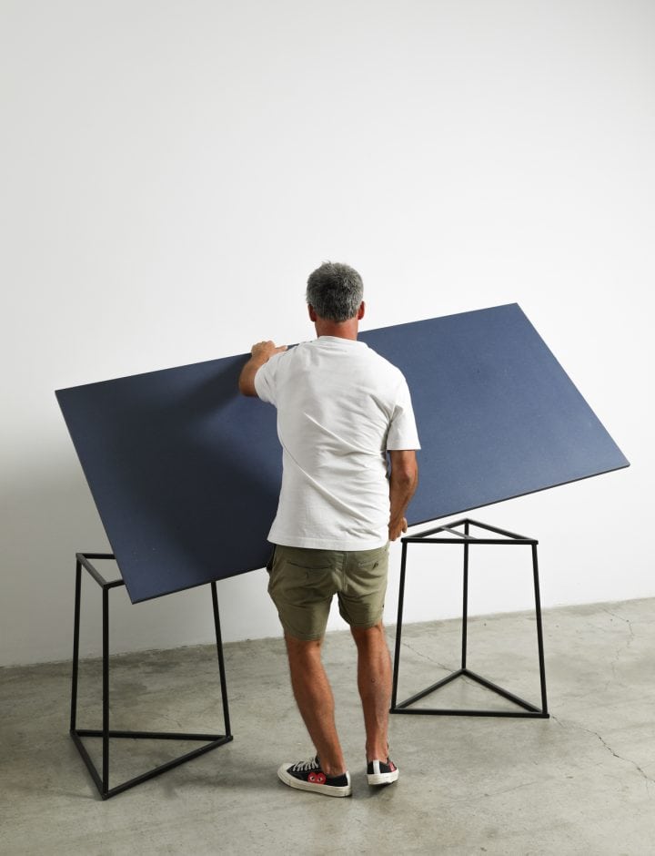 Persona colocando el tablero azul de la Mesa Kolor sobre los caballetes