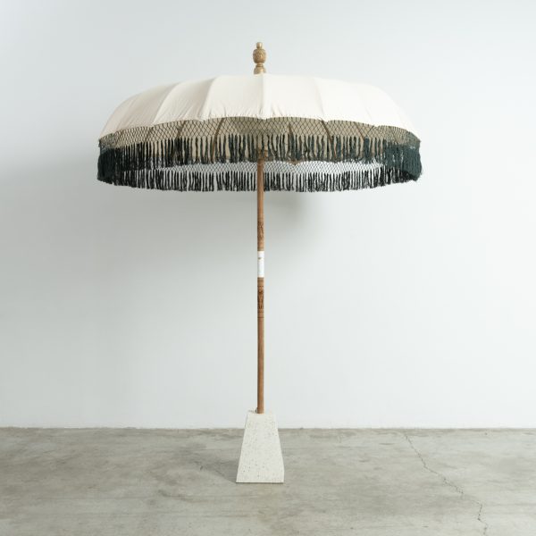 Parasol L blanco con flecos verdes y pie de terrazo para terrazas y cócteles al sol