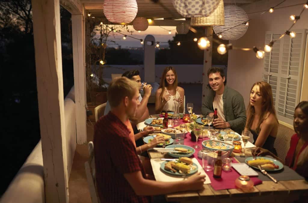 Bonfe team members and customers enjoy a meal together at a beautifully decorated outdoor table during dusk, with string lights and lanterns creating a warm ambiance at the Bonfe Insider gathering in August 2019.