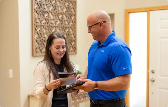 A Bonfe team member in a blue shirt discusses Membership Plan terms and conditions with a customer, reviewing documents together indoors near a white door.
