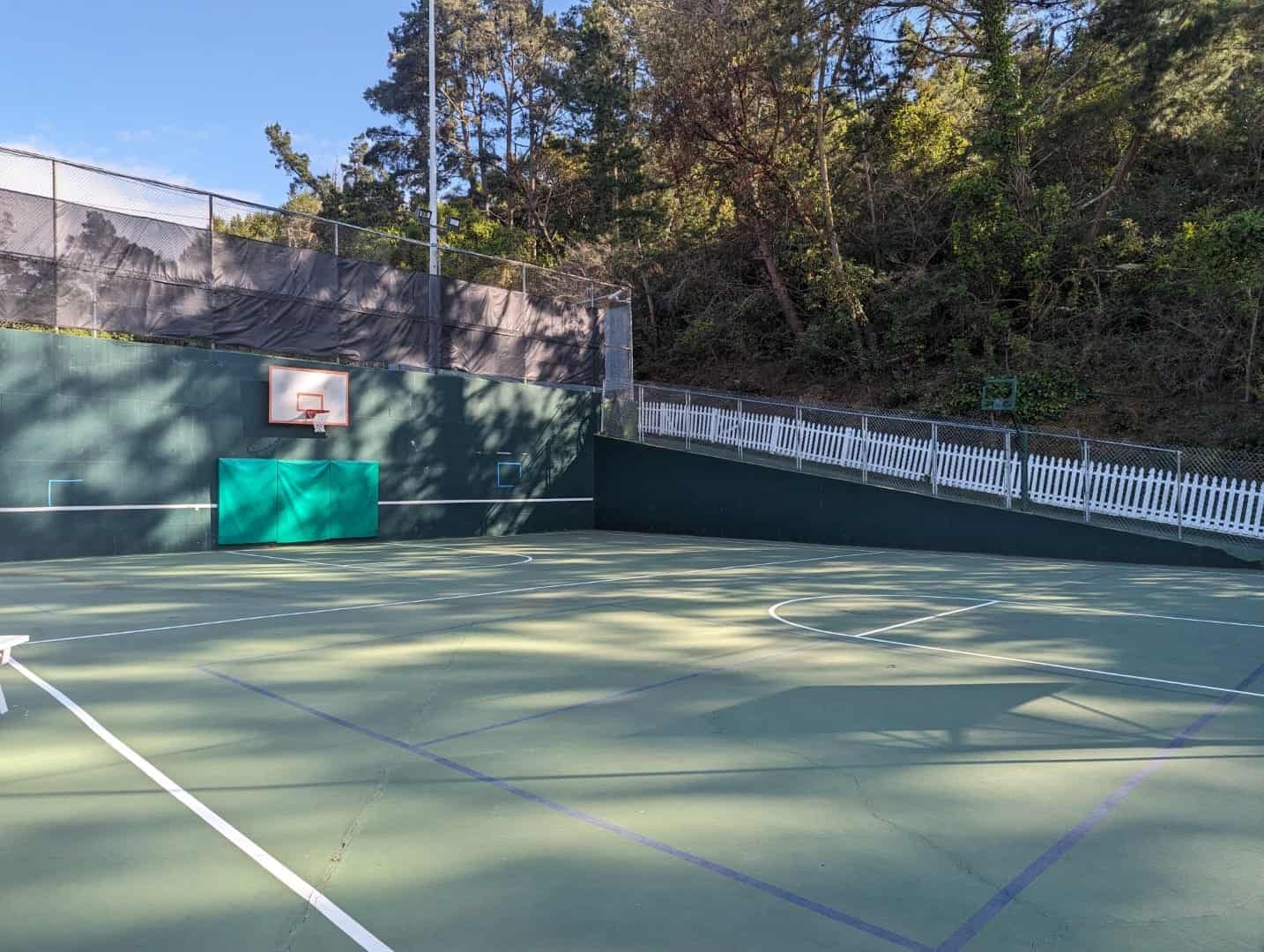 Basketball court at Bay-O-Vista Swim & Tennis Club with a surrounding natural landscape and fencing.