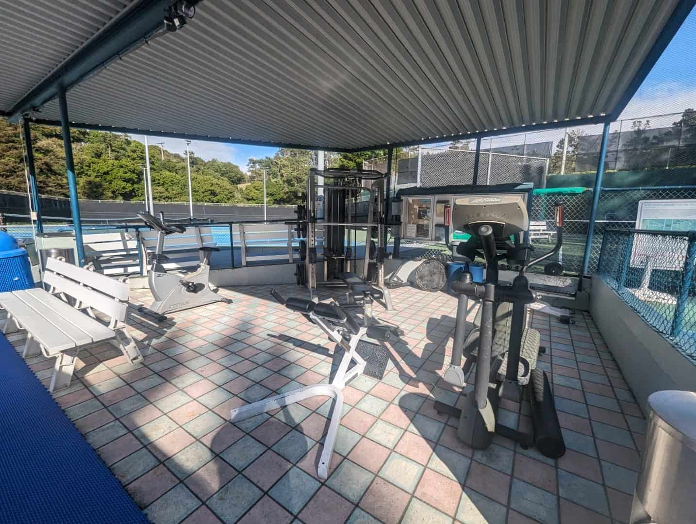 Modern outdoor fitness area at Bay-O-Vista Swim & Tennis Club with exercise equipment and shaded space for members.