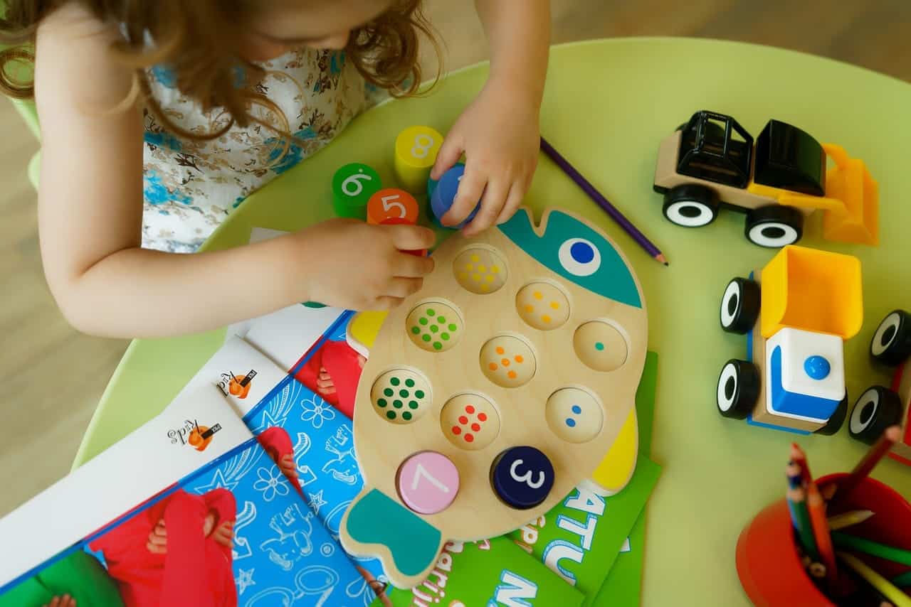Playing with colorful educational toys and wooden dice at Bay-O-Vista Swim & Tennis Club, promoting early childhood development and family fun activities.