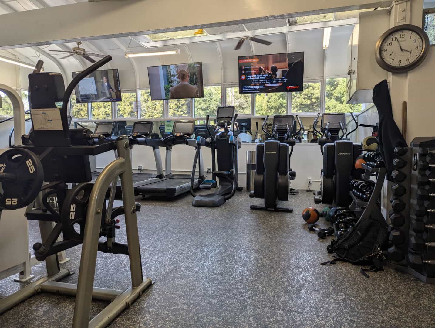 Modern gym equipment at Bay-O-Vista Swim & Tennis Club fitness center with cardio machines, free weights, and TVs for members' workout convenience.
