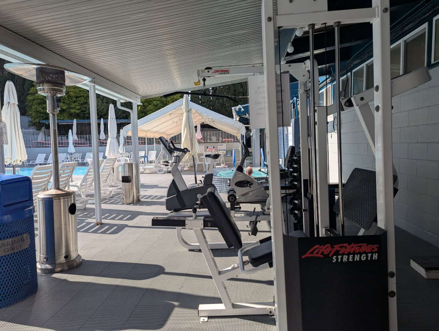 Modern fitness equipment with poolside view at Bay-O-Vista Swim & Tennis Club gym.