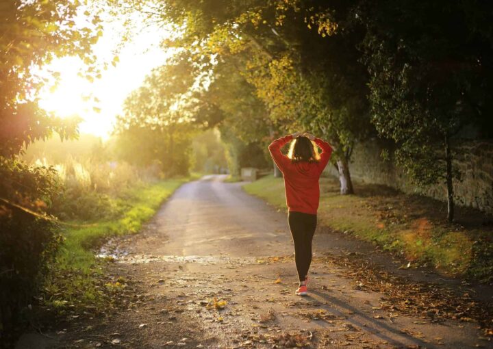 Bright woman walking on a scenic trail at sunset, enjoying nature and outdoor activities at Bay-O-Vista Swim & Tennis Club.