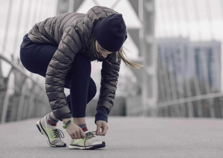 Active woman tying her running shoes outdoors in an urban setting.