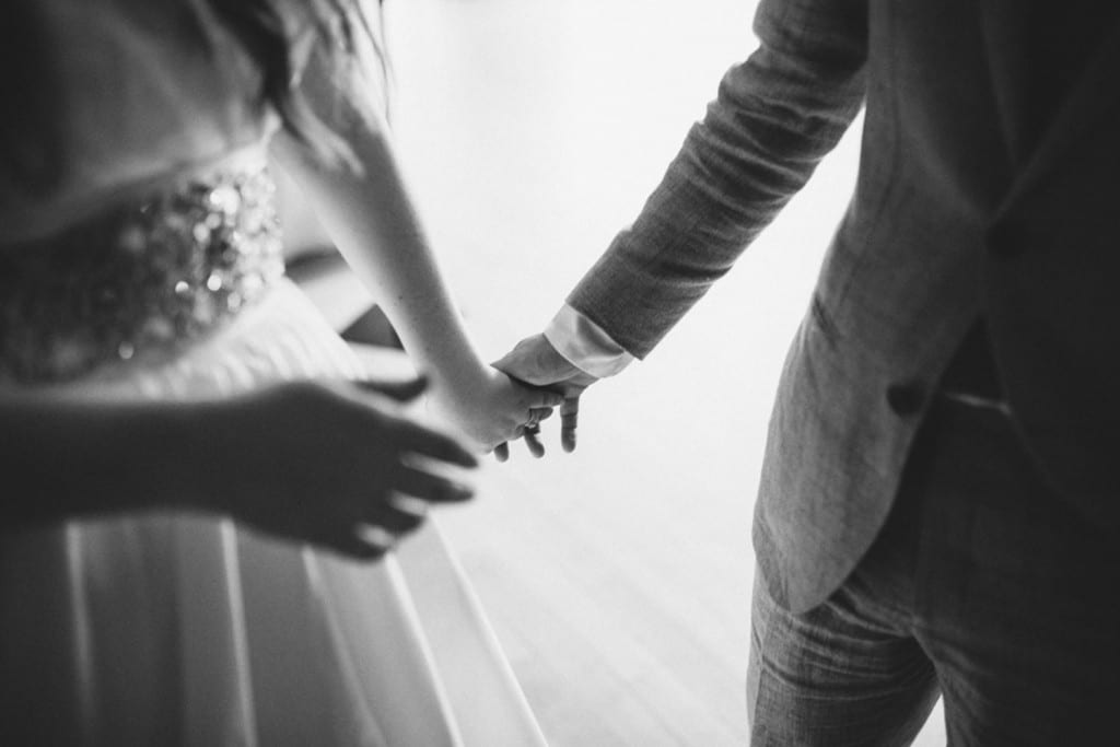 A black and white photo capturing the Silverthorne CO wedding of a bride and groom holding hands.
